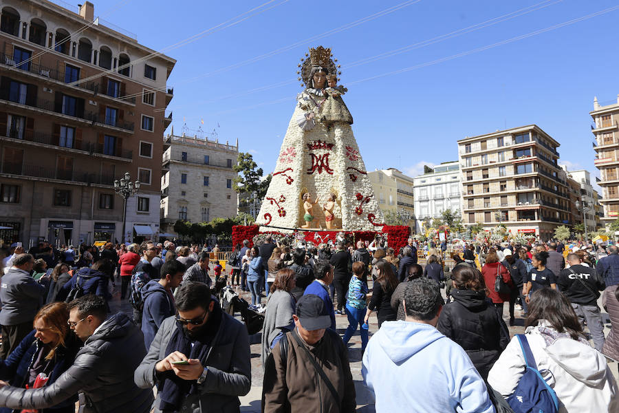 La Ofrenda concluyó este lunes después de que miles de falleros desfilaran para llevar las flores a la Virgen de los Desamparados. Este martes, a la luz del día se ha desvelado ante los ojos de los valencianos el aspecto definitivo del manto de la 'Geperudeta'. Claveles blancos, rojos y rosas componen componen el diseño del vestidor Rafael Chordá. Un floreado manto con el blanco como color predominante y que preside estos días la plaza de la Virgen, ante su basílica.