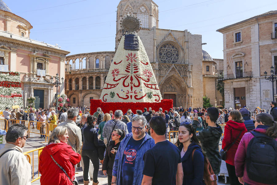 La Ofrenda concluyó este lunes después de que miles de falleros desfilaran para llevar las flores a la Virgen de los Desamparados. Este martes, a la luz del día se ha desvelado ante los ojos de los valencianos el aspecto definitivo del manto de la 'Geperudeta'. Claveles blancos, rojos y rosas componen componen el diseño del vestidor Rafael Chordá. Un floreado manto con el blanco como color predominante y que preside estos días la plaza de la Virgen, ante su basílica.