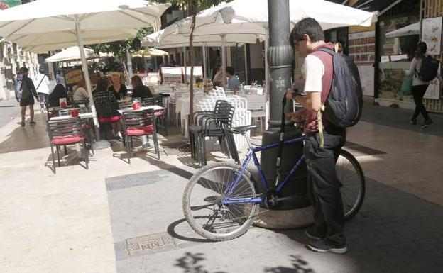 Un ciclista ata la bicicleta a una farola en el centro de Valencia. 