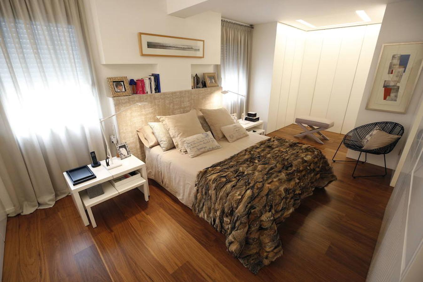 Las peticiones que Mariche Correcher planteó a la diseñadora creativa Carmen Bayarri estaban muy claras: que la casa tuviera muchos armarios, que la cocina y el salón estuviesen unidos pero a la vez se pudieran independizar y que la zona más tranquila de la casa albergara una suerte de suite en la que poder refugiarse después de la jornada de trabajo. Además le pidió que al entrar a la vivienda pudiera ver un ramo de flores. Con estas premisas, hace cuatro años se esbozó el proyecto en esta casa ubicada en una finca con carácter en pleno Ensanche valenciano. Para vestir el suelo escogieron madera de nogal, al igual que en las puertas que dividen las estancias. El resto de las puertas son blancas con las manivelas en negro y van de suelo a techo buscando potenciar la sensación de amplitud. En los baños instalaron porcelánico negro en el suelo que contrasta muy bien con el nogal. Carmen propuso ubicar junto a la entrada una escultura lacada flotante en rojo Ferrari que enmarca el espacio y permite ver el ramo de flores que reposa sobre la mesa del salón nada más entrar, que era uno de los deseos de la propietaria. La iluminación está integrada en la propia arquitectura. En lugar de obviar los pilares se decidió marcarlos de manera interna con filas de luz para ofrecer un ambiente casi escultórico. 