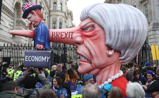 Varios manifestantes junto a una representación caricaturizada de Theresa May. 