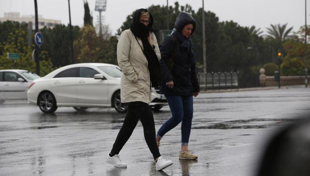 Dos mujeres se abrigan mientras caminan bajo la lluvia, ayer, en Valencia. 