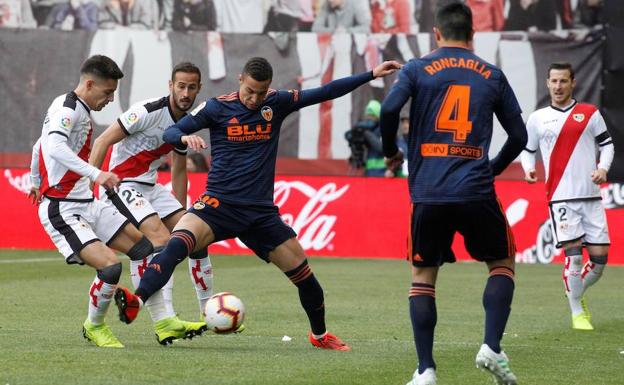 Rodrigo intenta llevarse el esférico ante dos jugadores del Rayo.