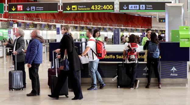 Varios pasajeros, ayer, ante uno de los mostradores de información del aeropuerto de Madrid-Barajas. 