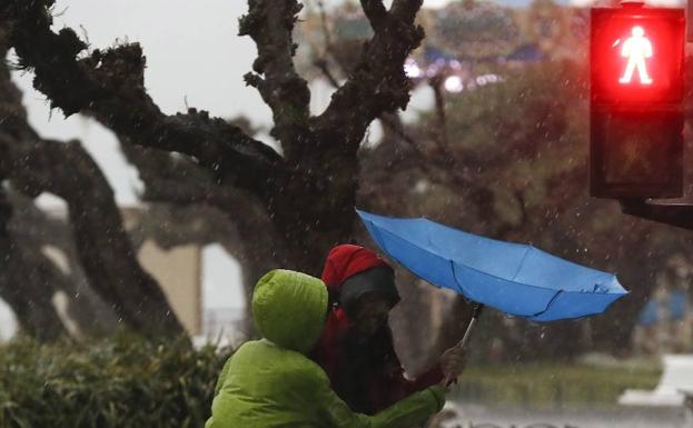 Unos turistas se protegen con un paraguas este lunes en el paseo de la Concha de San Sebastián. 