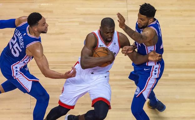 Serge Ibaka, defendido por dos jugadores de los Sixers. 