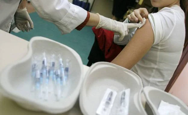 Un sanitario vacunando a una joven.