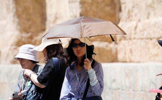 Una turista se resguarda del sol con un paraguas.