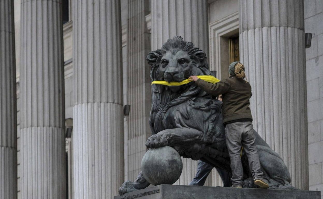 Un activista de Greenpeace amodarza uno de los leones de la puerta del Congreso.