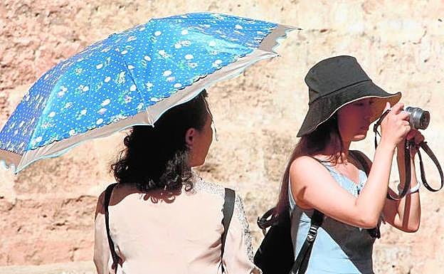 Turistas se protegen del sol en el centro de Valencia, ayer. 