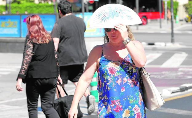 Una viandante se protege ayer del sol en Valencia.