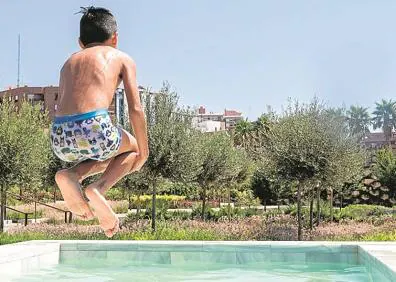 Imagen secundaria 1 - Un niño salta en otra de las piscinas improvisadas del Parque Central. Al lado, el cartel colocado por el Ayuntamiento. 