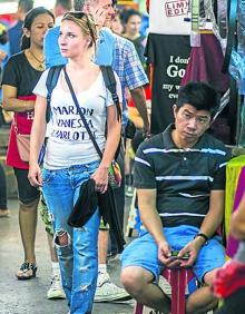 Imagen secundaria 2 - Chicas esperan a la entrada de un local. | Tuk tuks en el mercado nocturno. | Una turista recorre los puestos. 