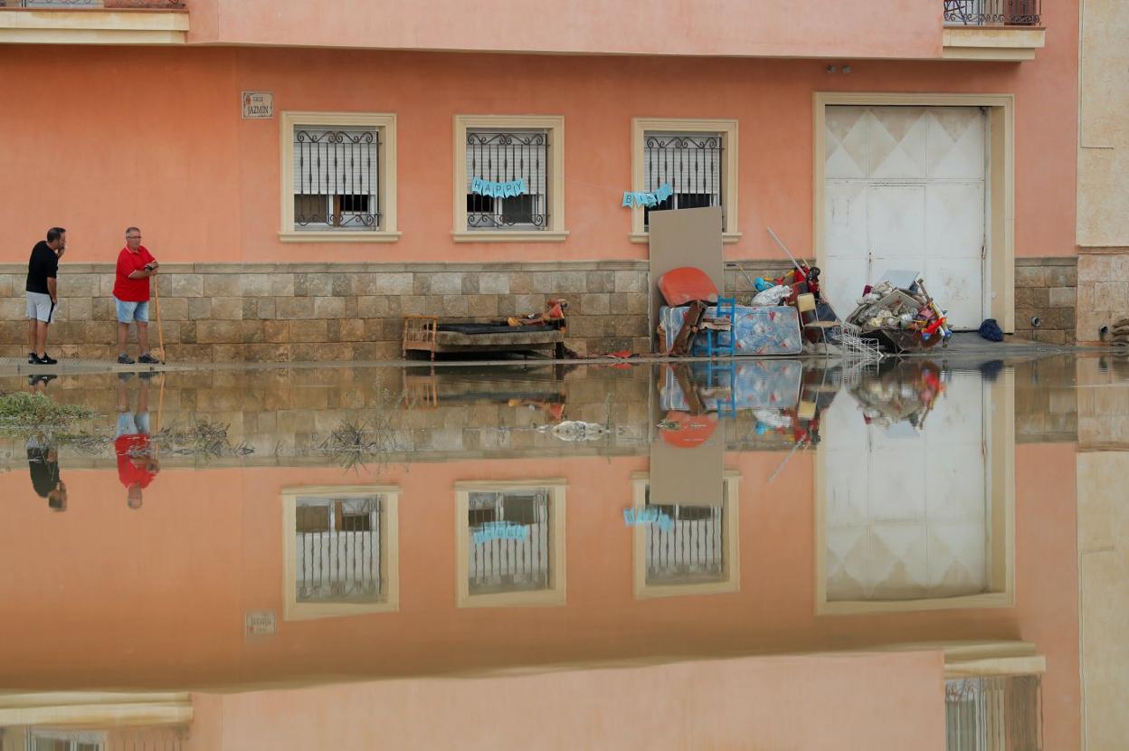 Dos vecinos observan una calle inundada en Almoradí. 