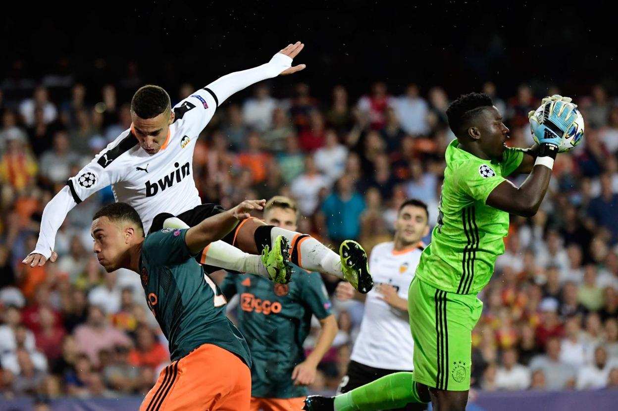 Onana atrapa el balón mientras Rodrigo cae sobre un jugador del Ajax. 