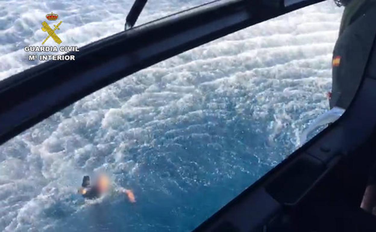 Uno de los guardias civiles que cayeron al mar pide ayuda al helicóptero del instituto armado.