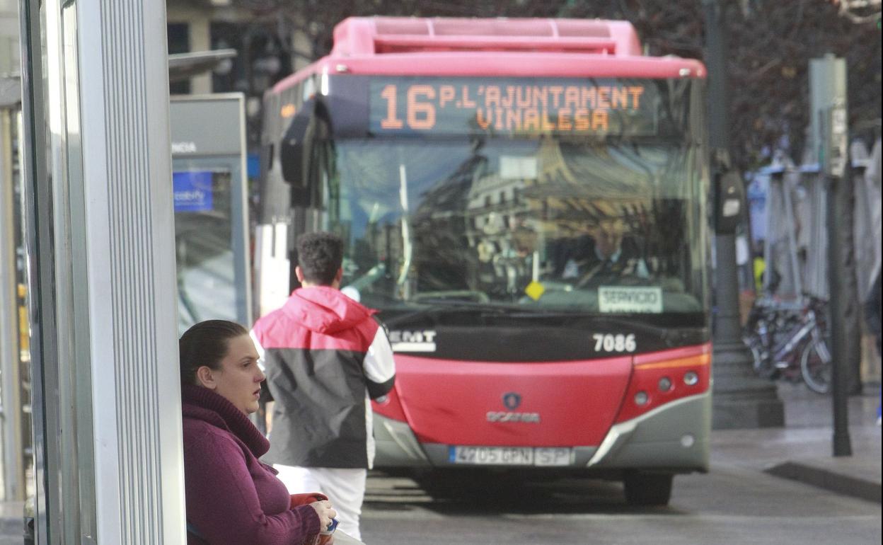 Una usuaria espera el autobús en una parada de la plaza del Ayuntamiento. 