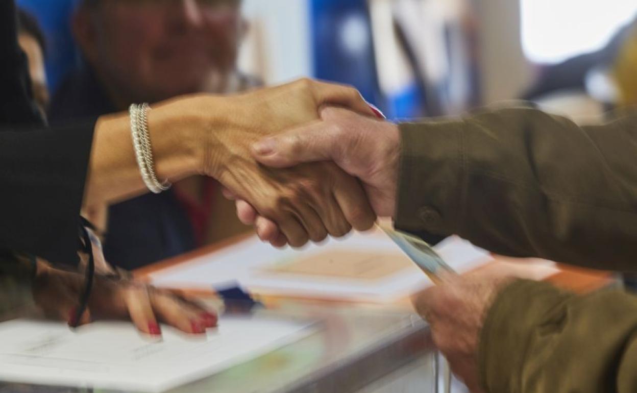 Un votante saluda a la presidenta de la mesa electoral tras ejercer su derecho a voto.