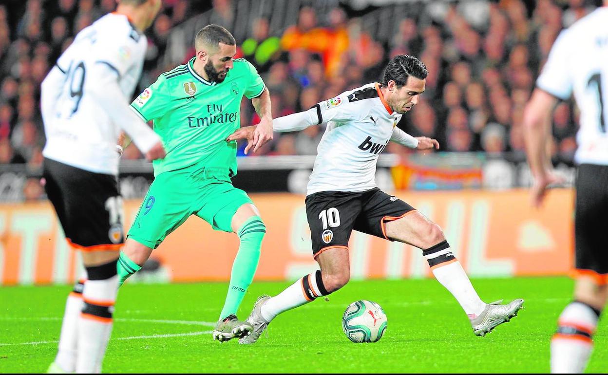 Parejo controla el balón ante la presión de Benzema.