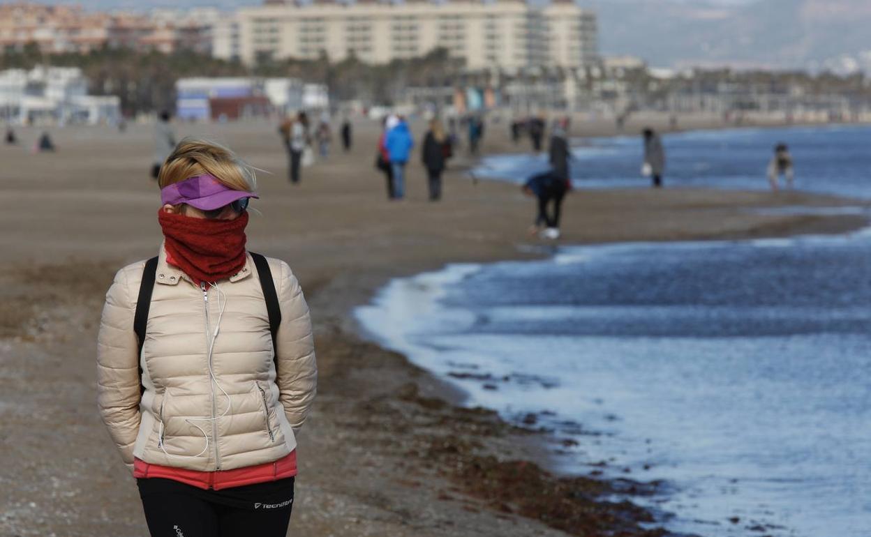 Una mujer se protege del frío, el viernes en la Malvarrosa.