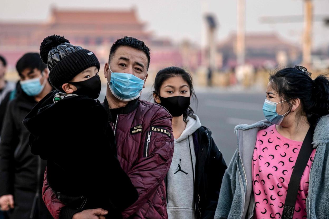 Una familia no olvida el uso de la máscara protectora durante su paseo por las inmediaciones de la plaza de Tiananmen, en Pekín. 