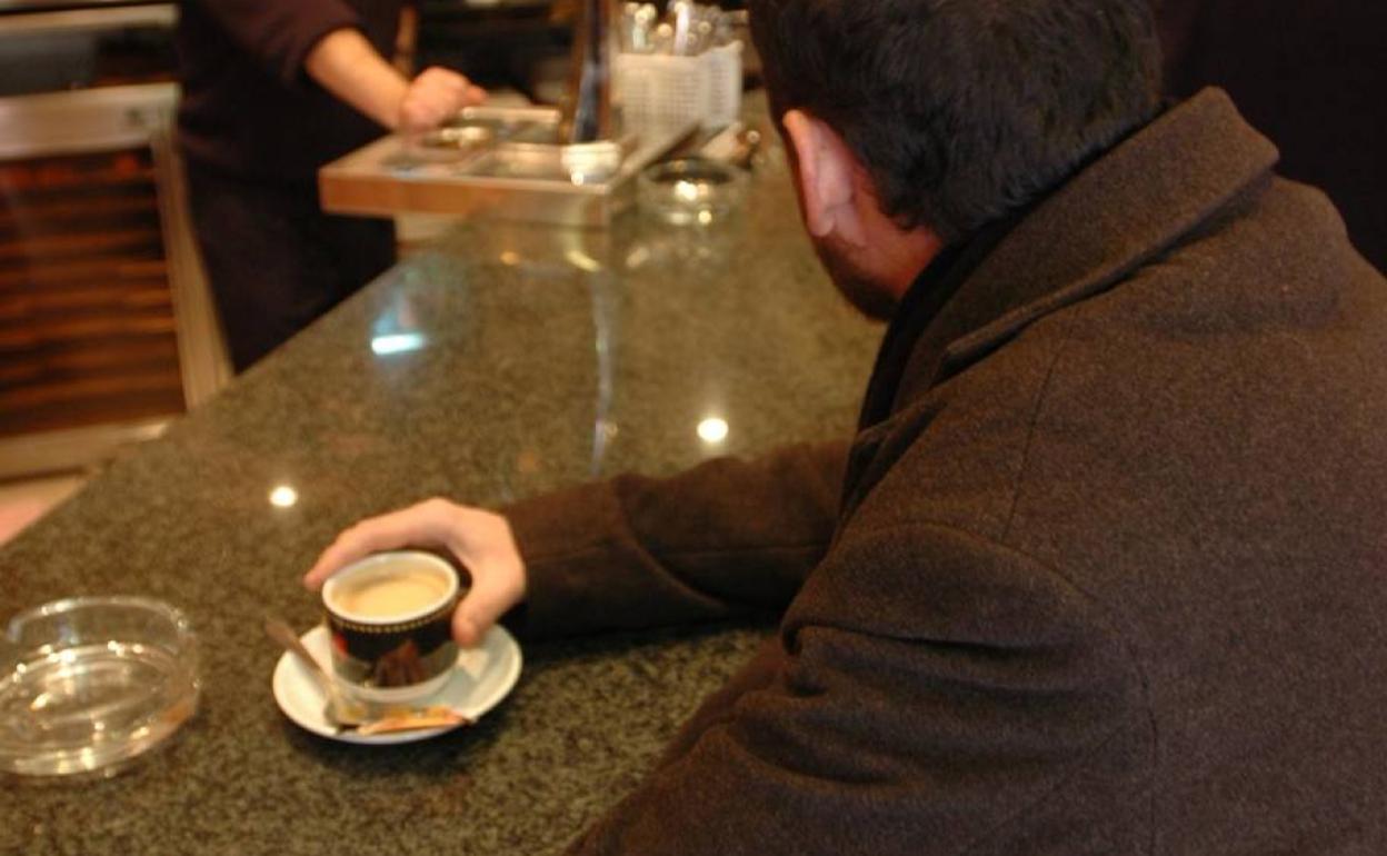 Un hombre tomando un café en un bar. 