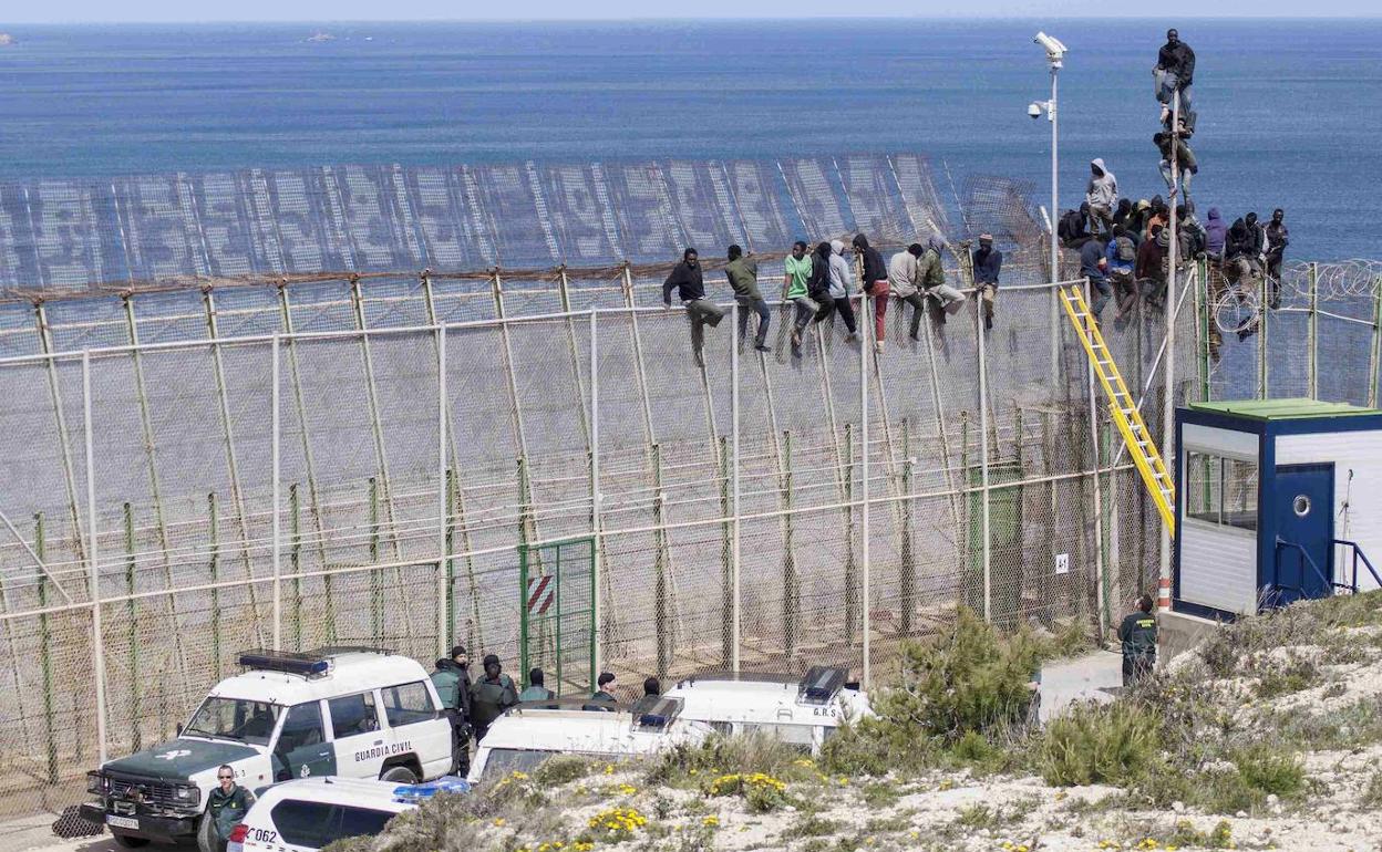 Un grupo de migrantes se encarama a la valla de Melilla en un salto masivo en abril de 2014.