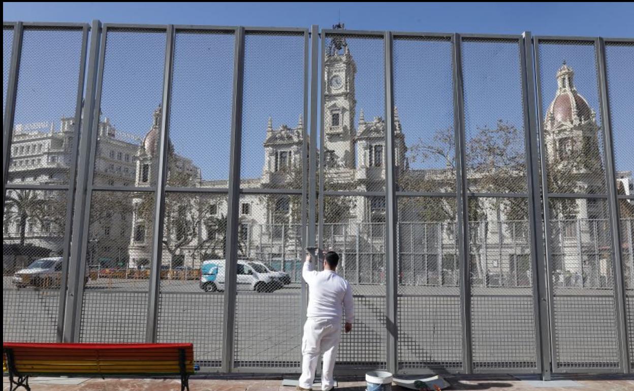 Un operario pinta la valla de la mascletà en la plaza del Ayuntamiento.