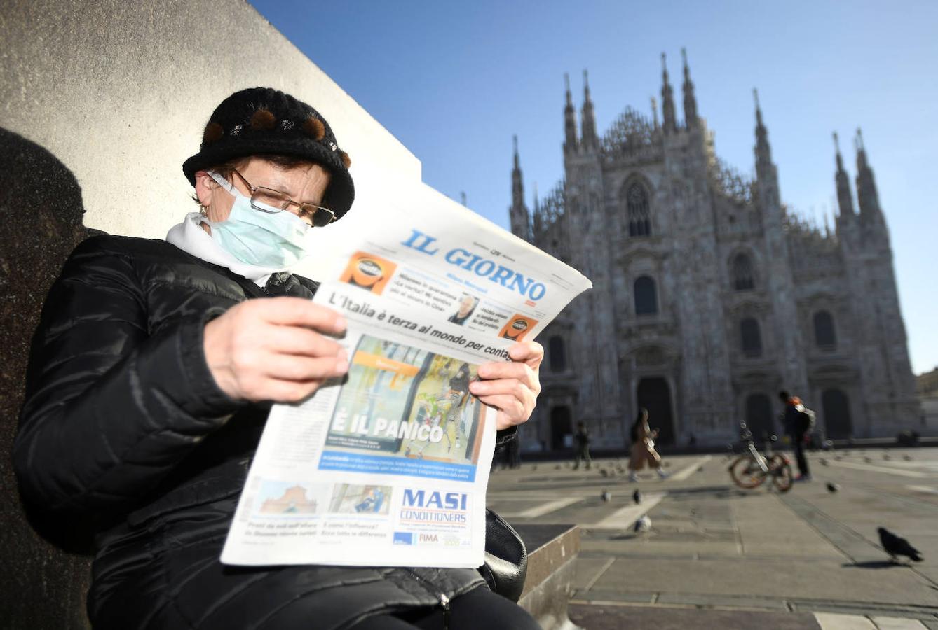 Una mujer lee un periódico junto a la catedral del Duomo.