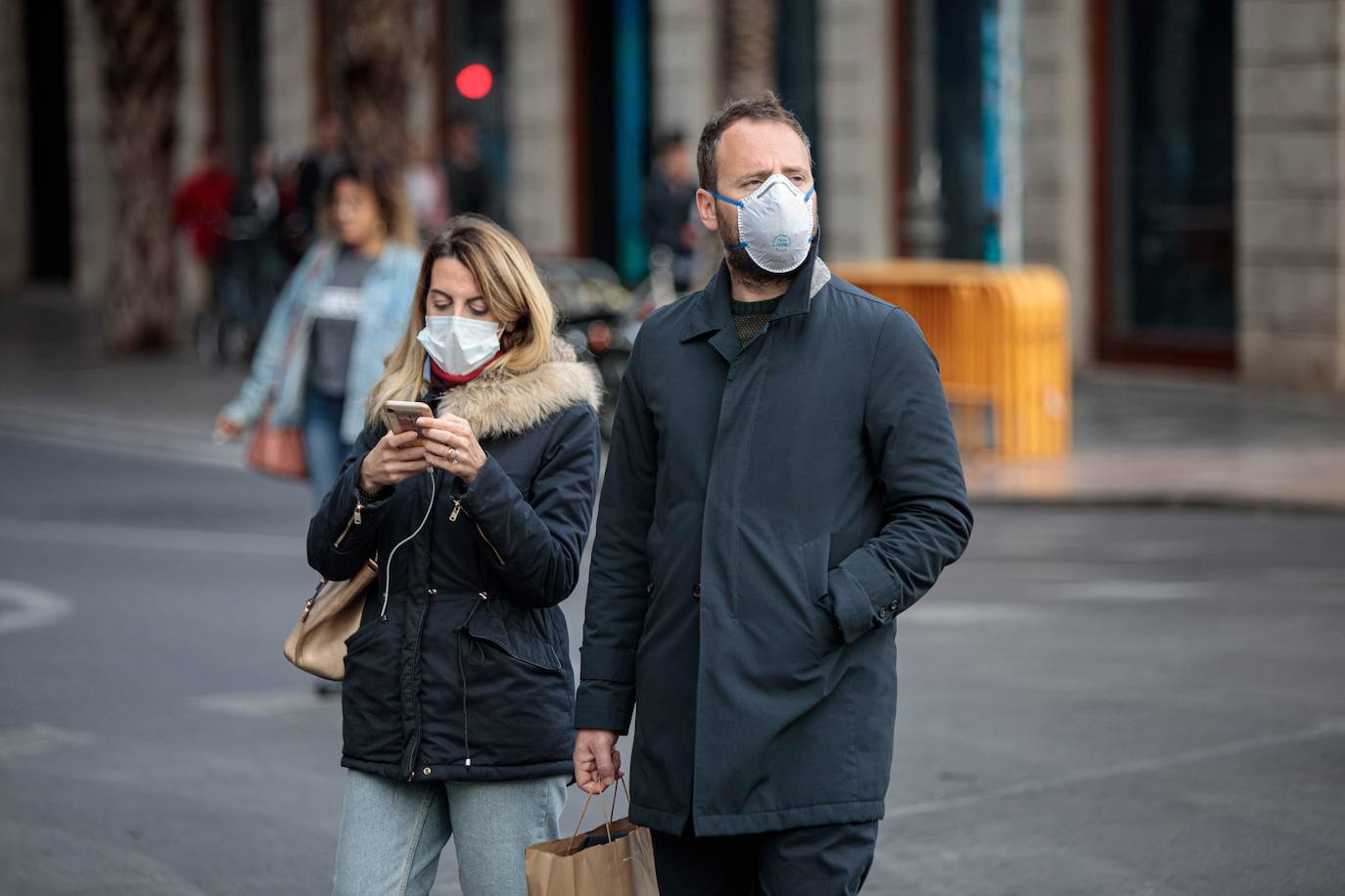 Dos personas pasean por una céntrica calle de València, tras el aplazamiento de las Fallas por coronavirus.