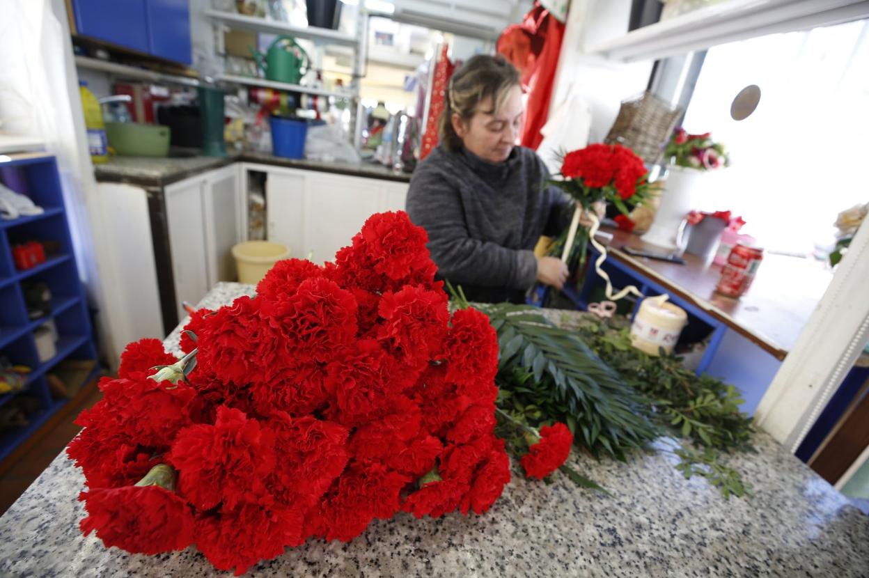 Florista arregla ramos
de claveles rojos antes
de conocer la noticia
de la cancelación
de las Fallas. j. signes