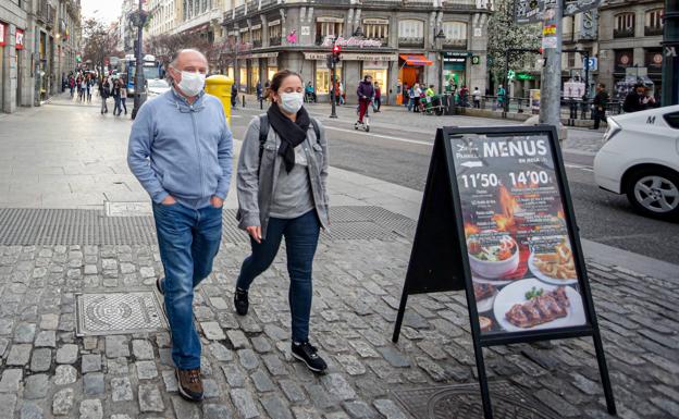 Dos personas pasean por el centro de Madrid con mascarillas como medida de protección frente al coronavirus. 