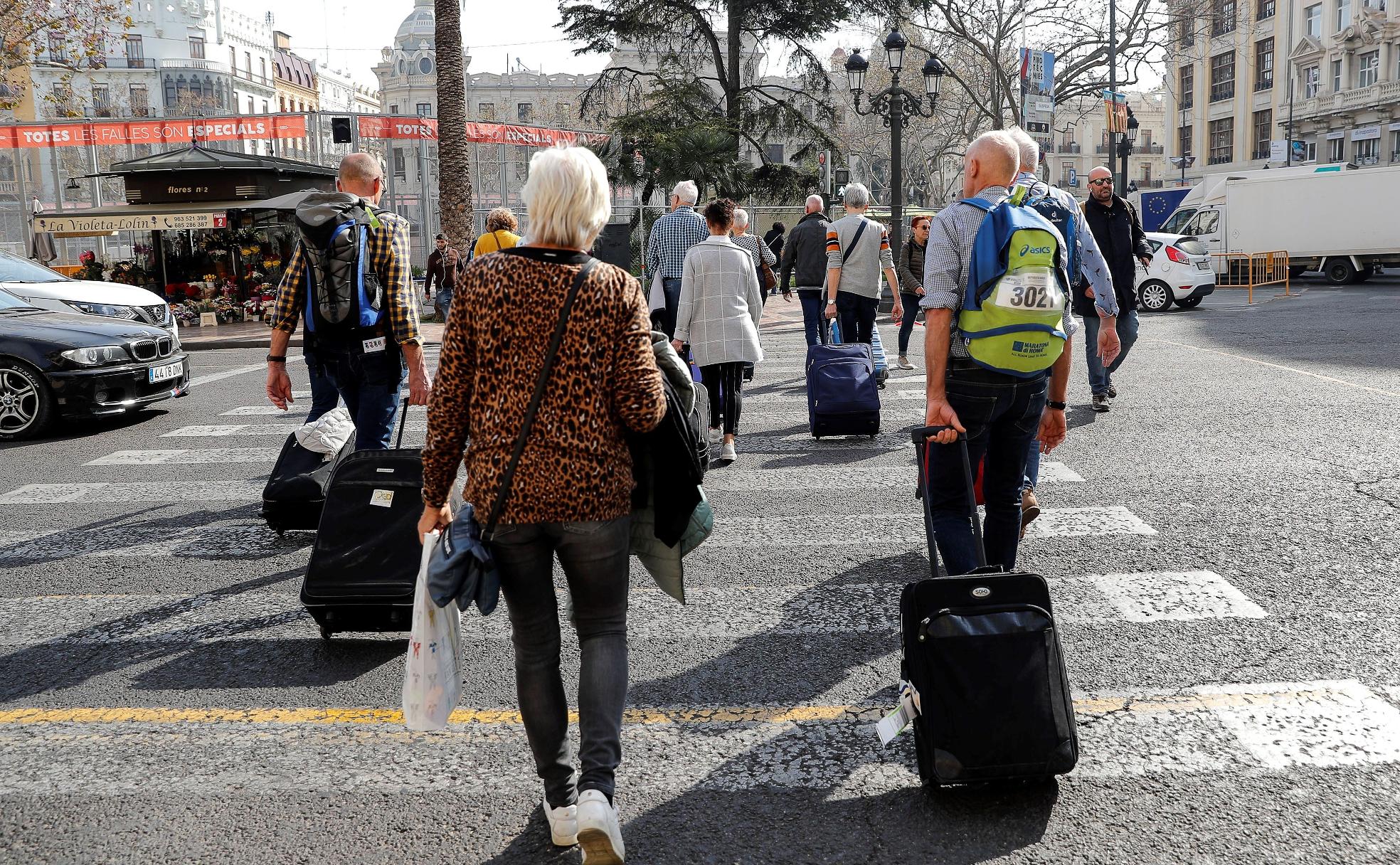 Un grupo de turistas recién llegados a Valencia cruzan por la céntrica plaza del Ayuntamiento. 