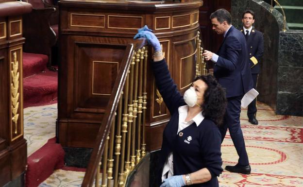 Una trabajadora de la limpieza desinfecta la barandilla del Congreso, este miércoles en el Congreso, durante una de las intervenciónes del presidente del Gobierno, Pedro Sánchez