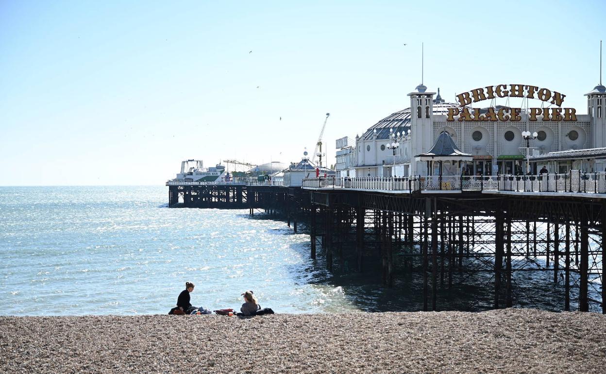 Dos personas sentadas en la playa en Brighton, Reino Unido