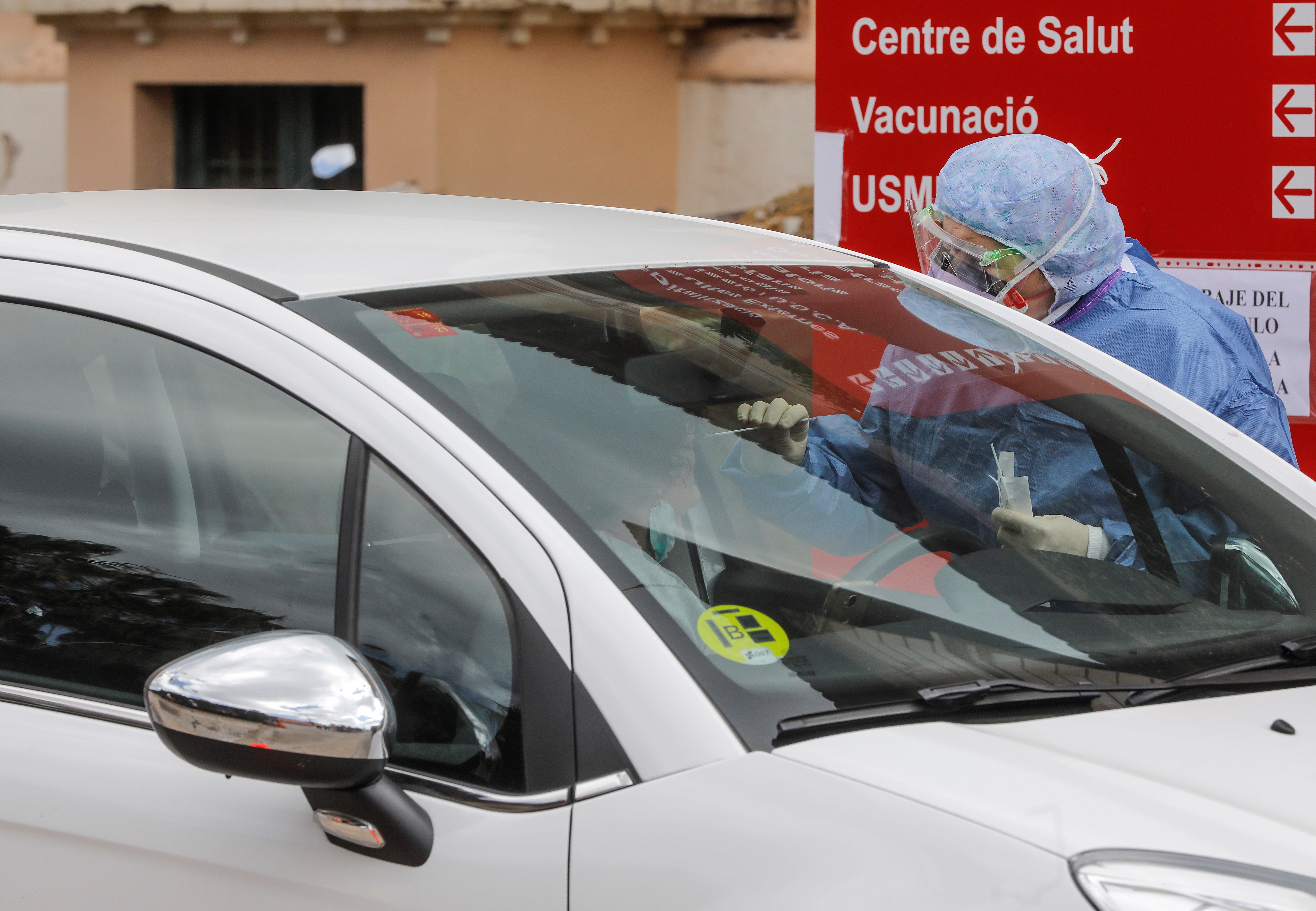 Miembros del hospital de la Malvarrosa, en Valencia, realizan tomas de muestra rápidas al personal sanitario sin que los conductores bajen del vehículo. 