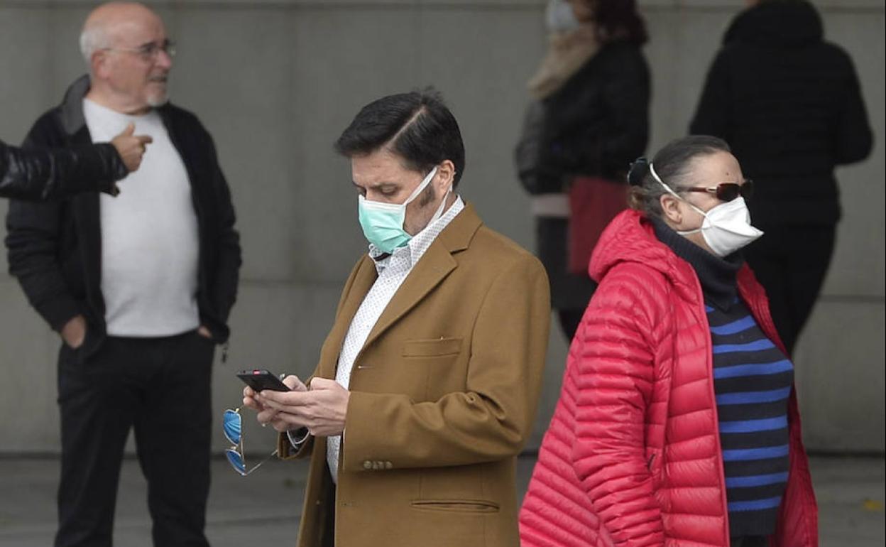 Dos ciudadanos se protegen con mascarilla .