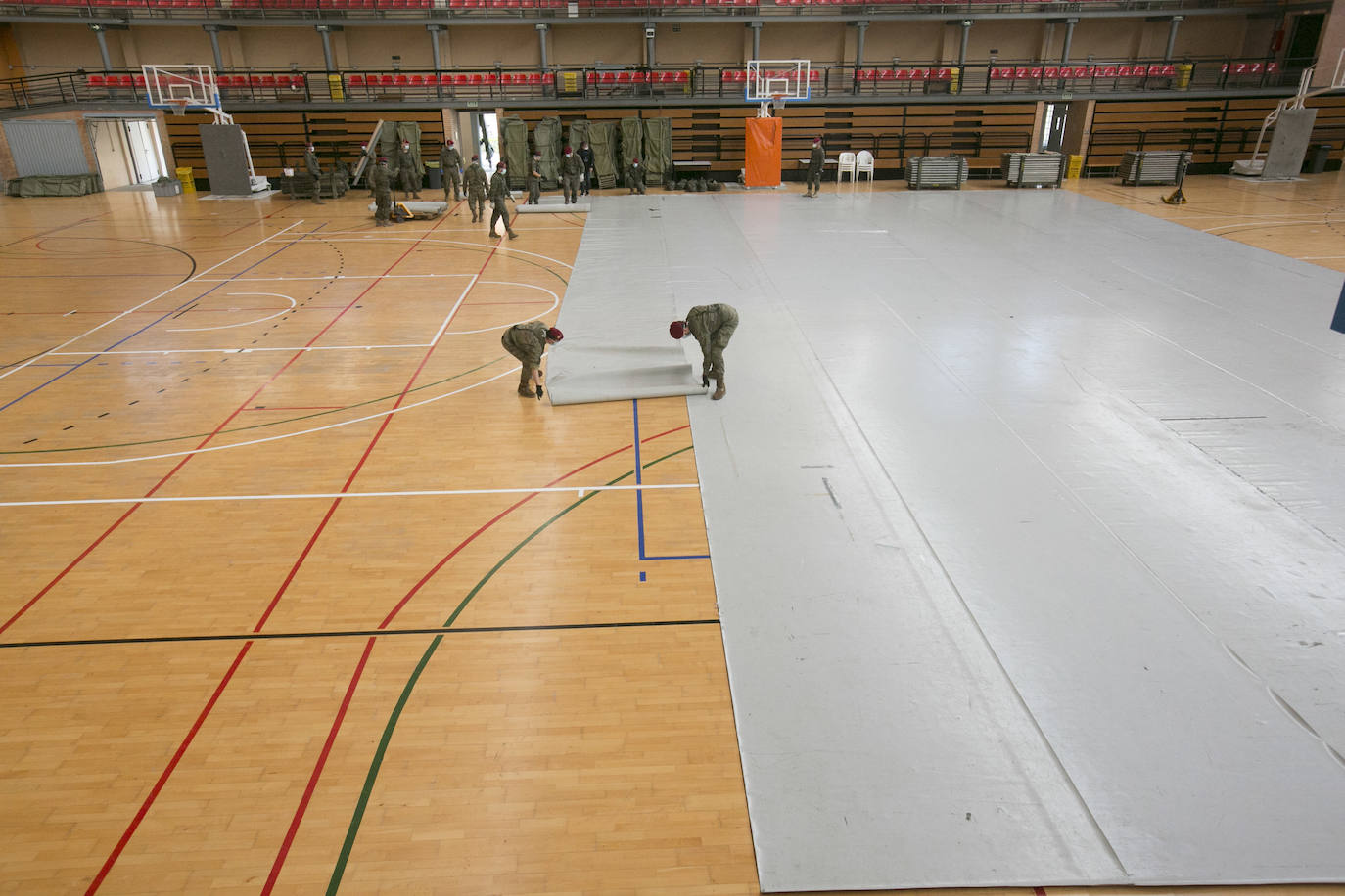 Militares del ejército colocan los materiales necesarios para adecuar el polideportivo del Cabanyal en un albergue para personas sin techo.