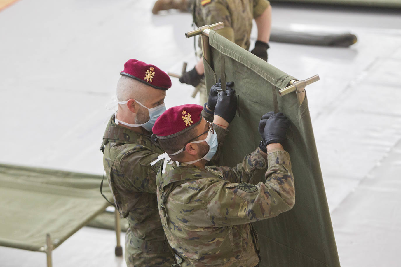 Militares del ejército colocan los materiales necesarios para adecuar el polideportivo del Cabanyal en un albergue para personas sin techo. 