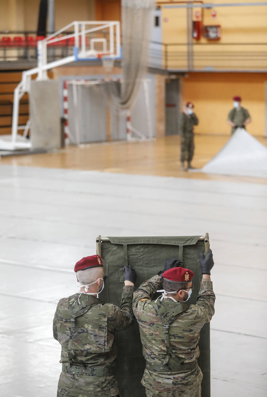 Militares del ejército colocan los materiales necesarios para adecuar el polideportivo del Cabanyal en un albergue para personas sin techo.