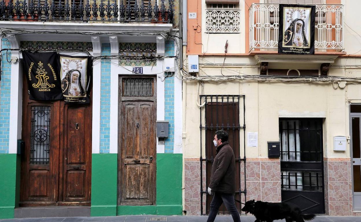 Un vecino pasea su perro por una calle del Cabanyal. 