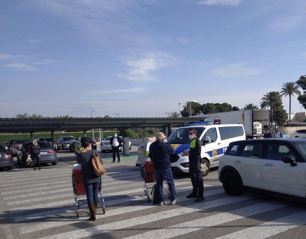 Un agente conversa con un ciudadano a la salida de un supermercado en Alicante. LP