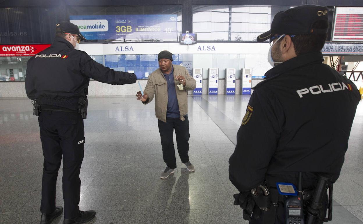 Dos agentes reparten mascarillas en la estación de autobuses de Valencia. 