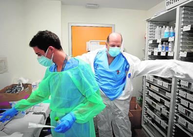 Imagen secundaria 1 - 1. Un paciente con fallos multiorgánicos recibe medicación en la Unidad de Cuidados Intensivos del Hospital la Fe. 2. El protocolo para la colocación y retirada de los trajes de protección es muy riguroso. Mientras uno se lo pone un compañero repasa cada fase. 