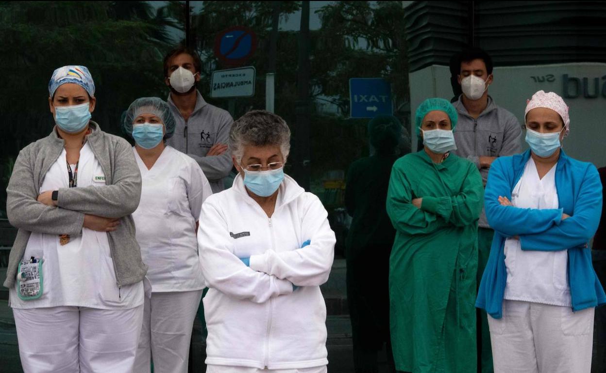 Sanitarios del Hospital La Fe de Valencia guardan un minuto de silencio por las víctimas del coronavirus, este domingo. 