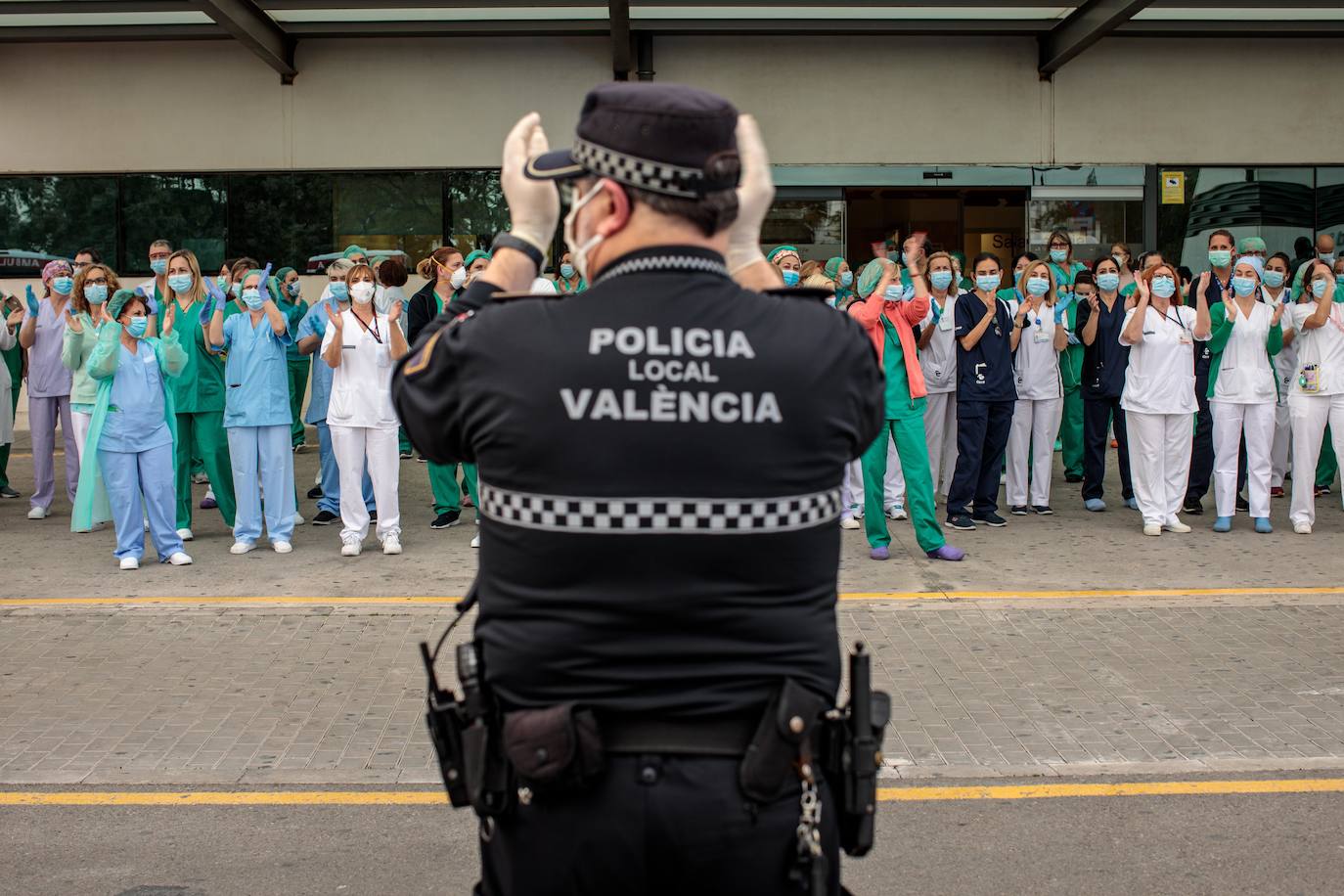 Un policía local y sanitarios del Hospital La Fe de Valencia, durante el aplauso diario en apoyo a todo el personal por su labor en la crisis del coronavirus