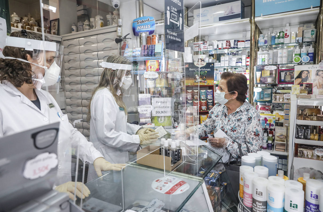 Dos farmacéuticas dan una mascarilla a una mujer durante el reparto de mascarillas gratuitas contra el Covid-19 a mayores de 65 años y colectivos de riesgo en Valencia