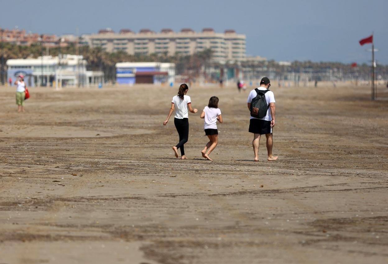 Una familia paseando ayer por la playa con la bandera roja al fondo. txema rodríguez