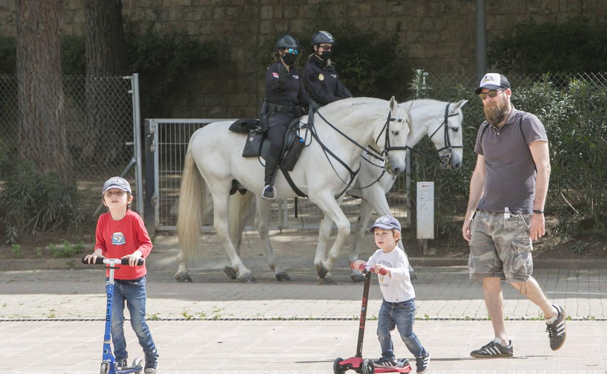 Agentes de policía vigilando el paseo de padres con menores en el jardín del Turia. 