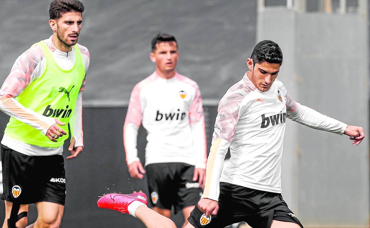 Guedes chuta con su pierna derecha, con Piccini detrás y Guillamón al fondo, en un entrenamiento del Valencia en Paterna.